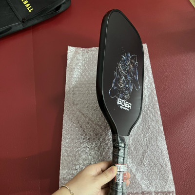 Vợt Pickleball PK03 nặng 220g, bề mặt dày 14mm từ sợi carbon, màu đen huyền bí cùng hình in nhiệt sắc nét đạt tiêu chuẩn kỹ thuật của USAPA chấp thuận để sử dụng trong thi đấu.